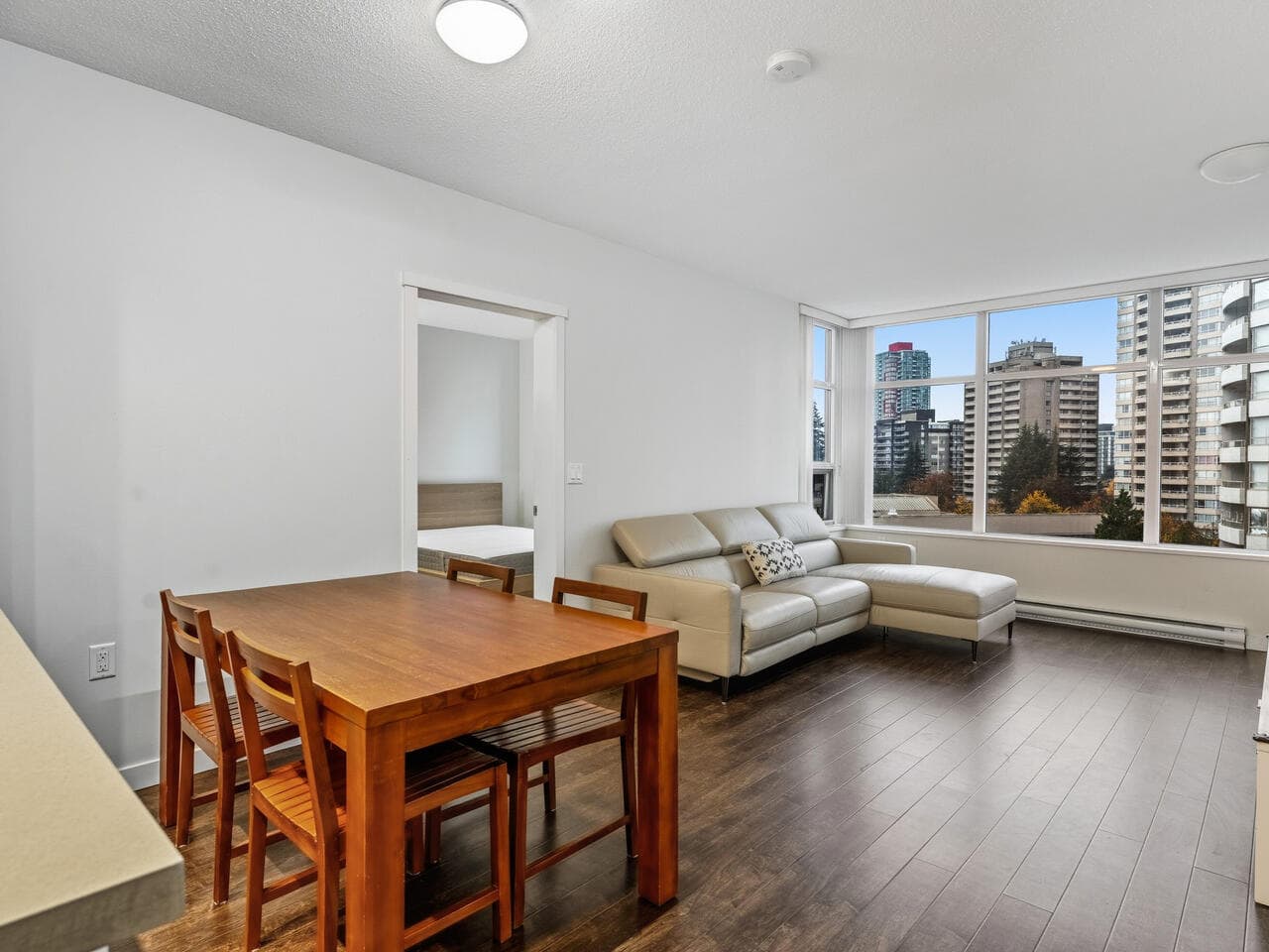 Modern Vancouver city skyline views from downtown condo living room with hardwood floors and contemporary decor.