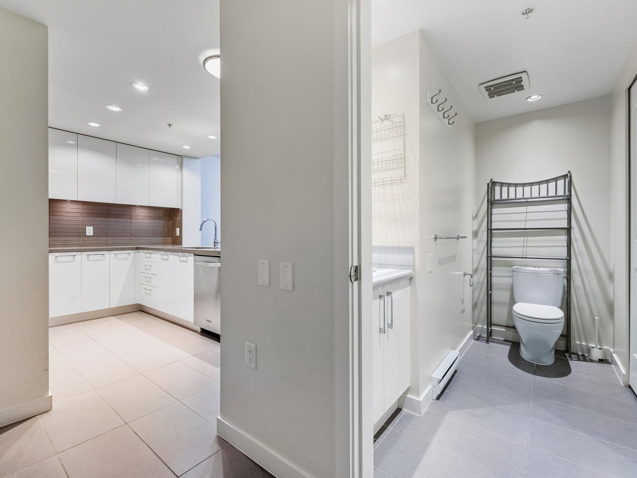 Modern kitchen and bathroom interior in a contemporary condo at Orca Realty Inc. featuring white cabinetry, sleek designs, and minimalist decor in a prime Vancouver property.