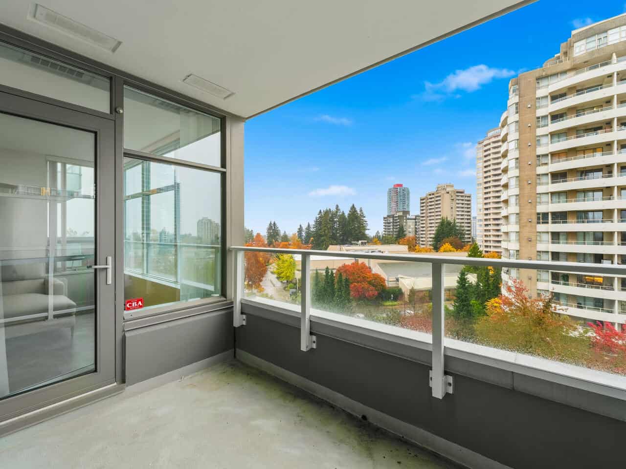 Modern condo balcony with city skyline views, high-rise buildings, and vibrant fall foliage, perfect for urban living in Vancouver.
