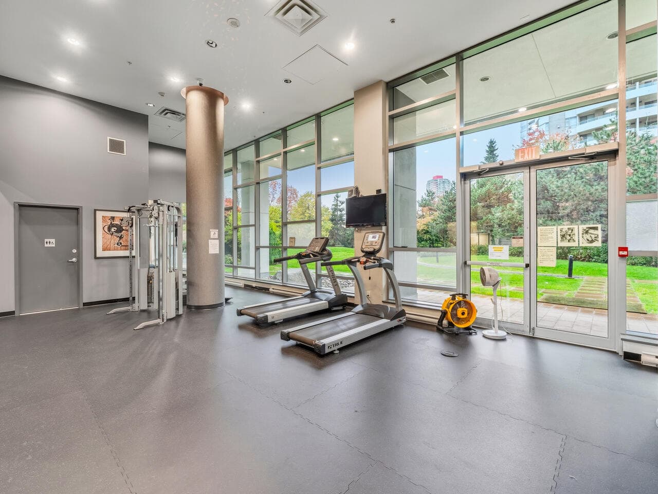 Modern gym fitness center with cardio equipment, large windows with cityscape view, and a clean, inviting atmosphere - ideal for health-conscious residents at Orca Realty Inc.