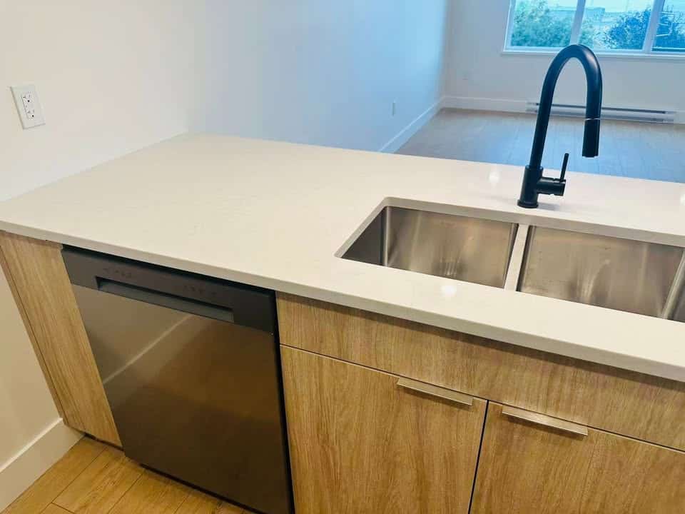 Modern kitchen with stainless steel sink and black faucet in a contemporary home.