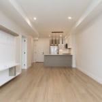 Modern open-concept kitchen and living space in a contemporary Vancouver apartment, featuring minimalist design, hardwood flooring, and stainless steel appliances, perfect for luxury urban living.