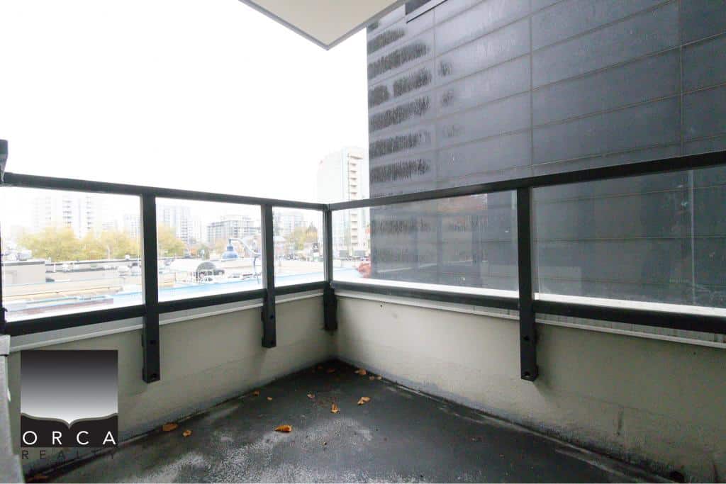 Spacious modern balcony with city views, black metal railing, and urban architecture, perfect for relaxing or entertaining. Located in Vancouver, BC.