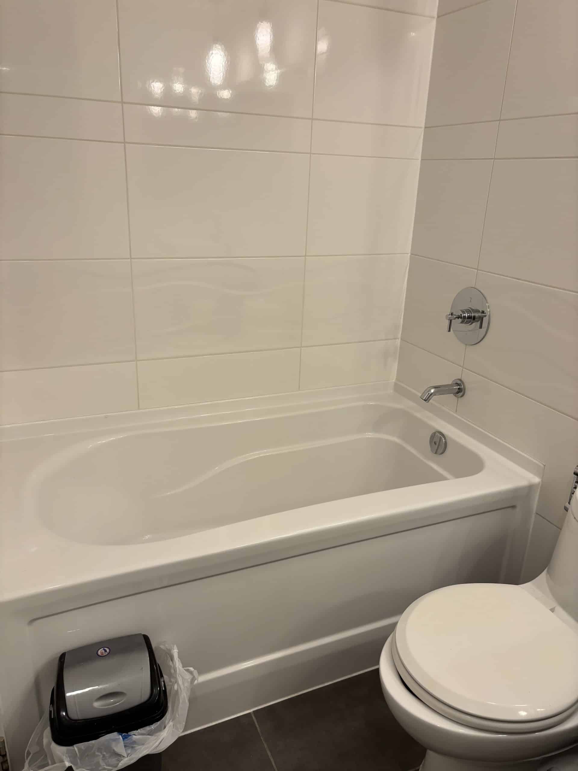 A clean, modern bathroom featuring a white bathtub, a toilet, and tiled walls, ideal for residential living. Perfect for showcasing property amenities in Vancouver real estate listings.