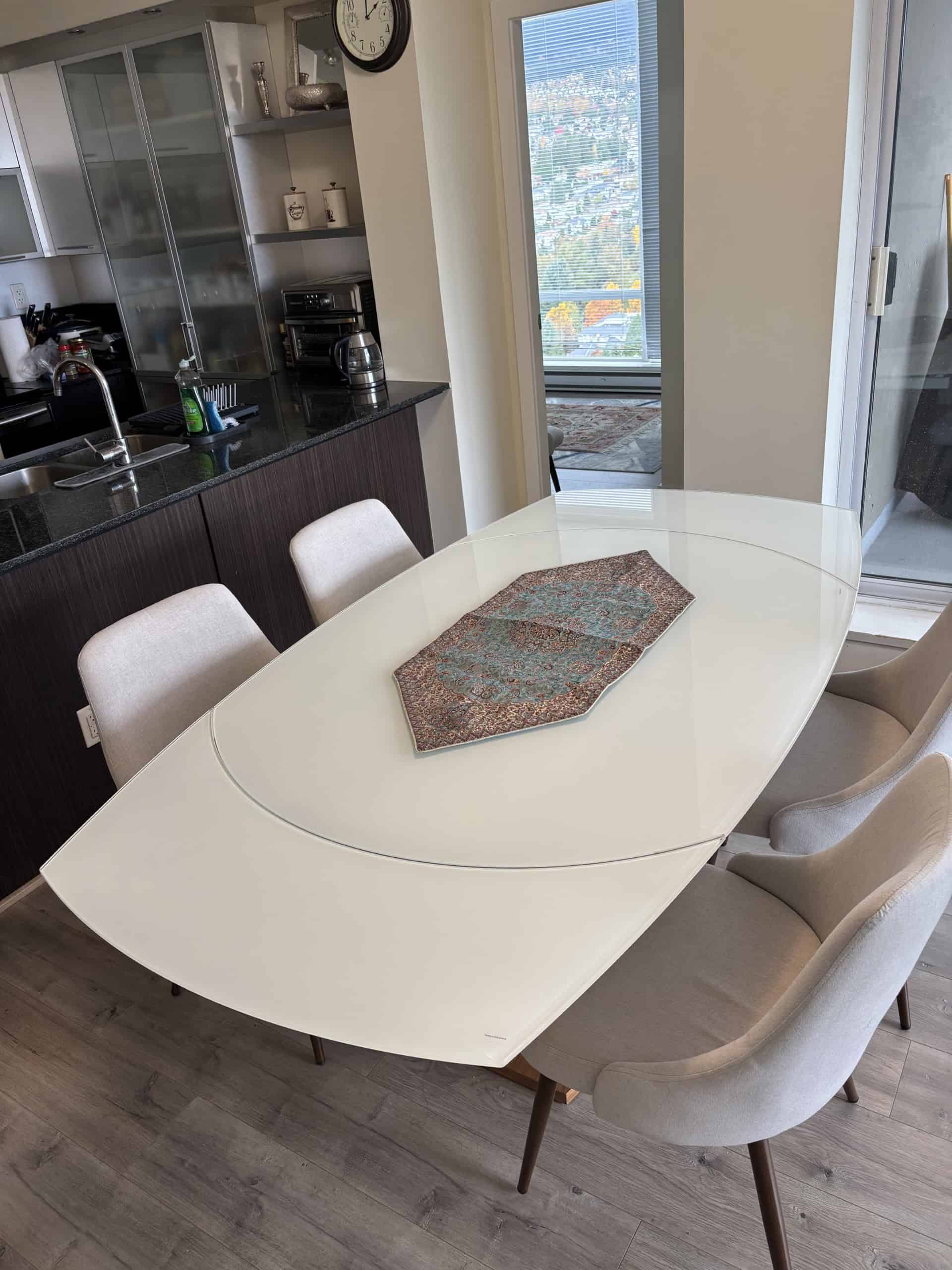 Modern dining area with elegant beige chairs and a sleek white table near a balcony with city views, ideal for Vancouver real estate and property listings by Orca Realty Inc.