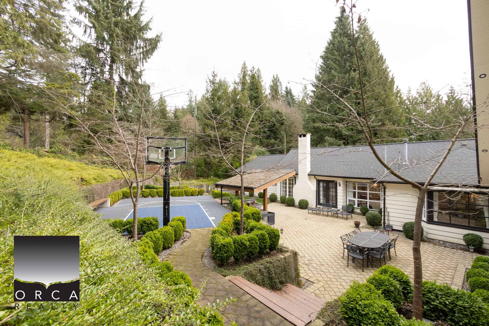Spacious laneway house with a private backyard, outdoor seating, and a basketball court in West Vancouver, perfect for family living and outdoor activities.