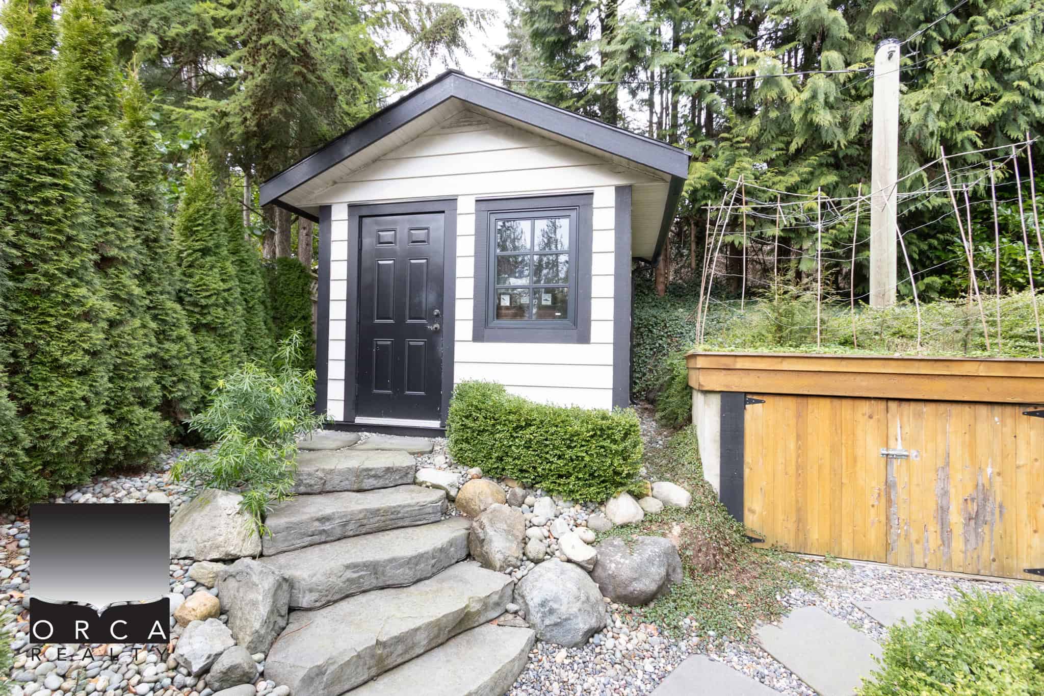 Cozy laneway house in West Vancouver with stone steps, lush greenery, and modern exterior, ideal for guest accommodation or rental income.
