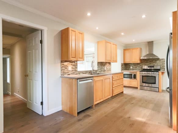 Bright modern kitchen with natural wood cabinets, stainless steel appliances, and stylish backsplash, ideal for comfortable home living in Ontario.