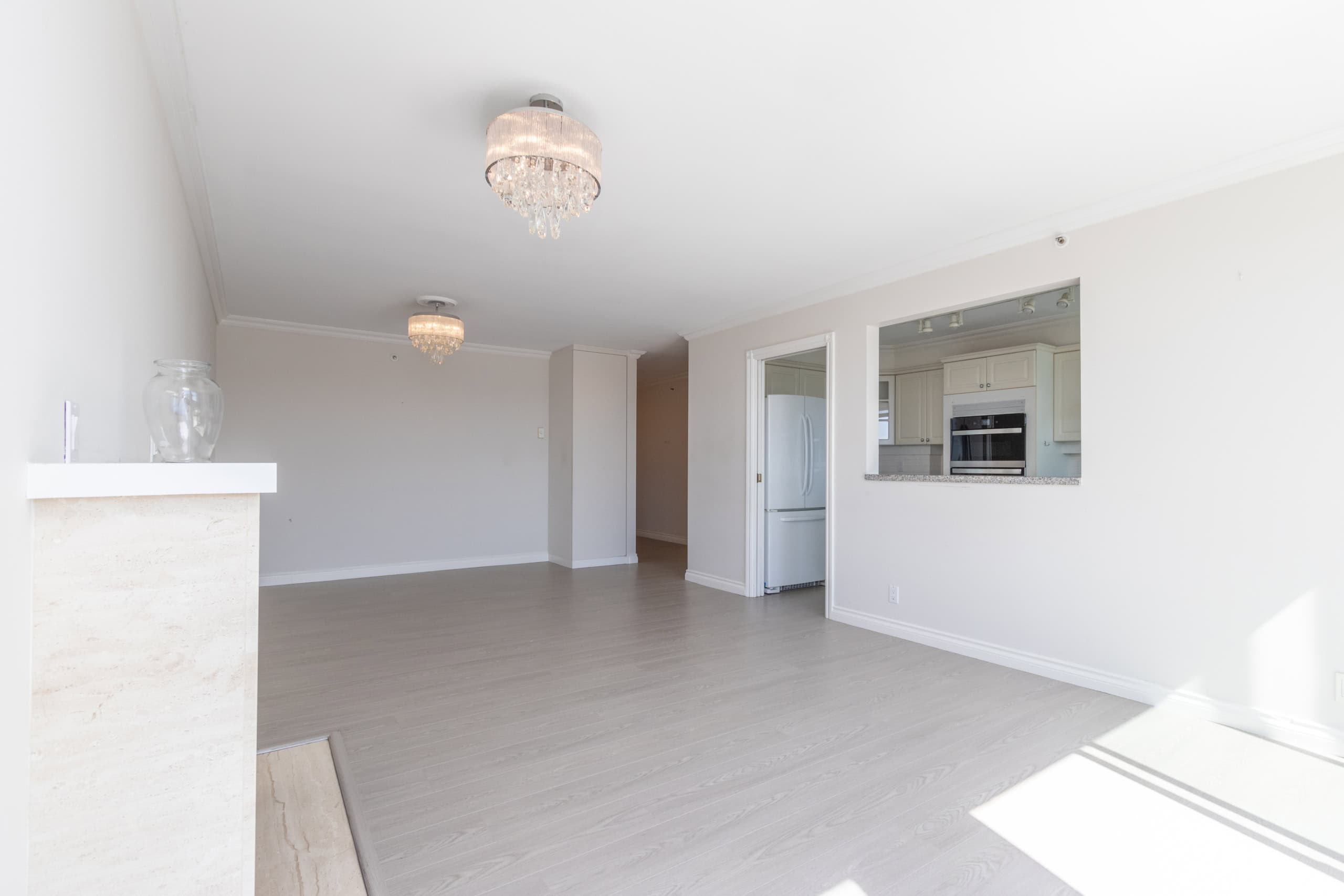 Spacious, modern living room with light-coloured flooring and elegant chandeliers, showcasing open-concept design perfect for Bay Area homes.