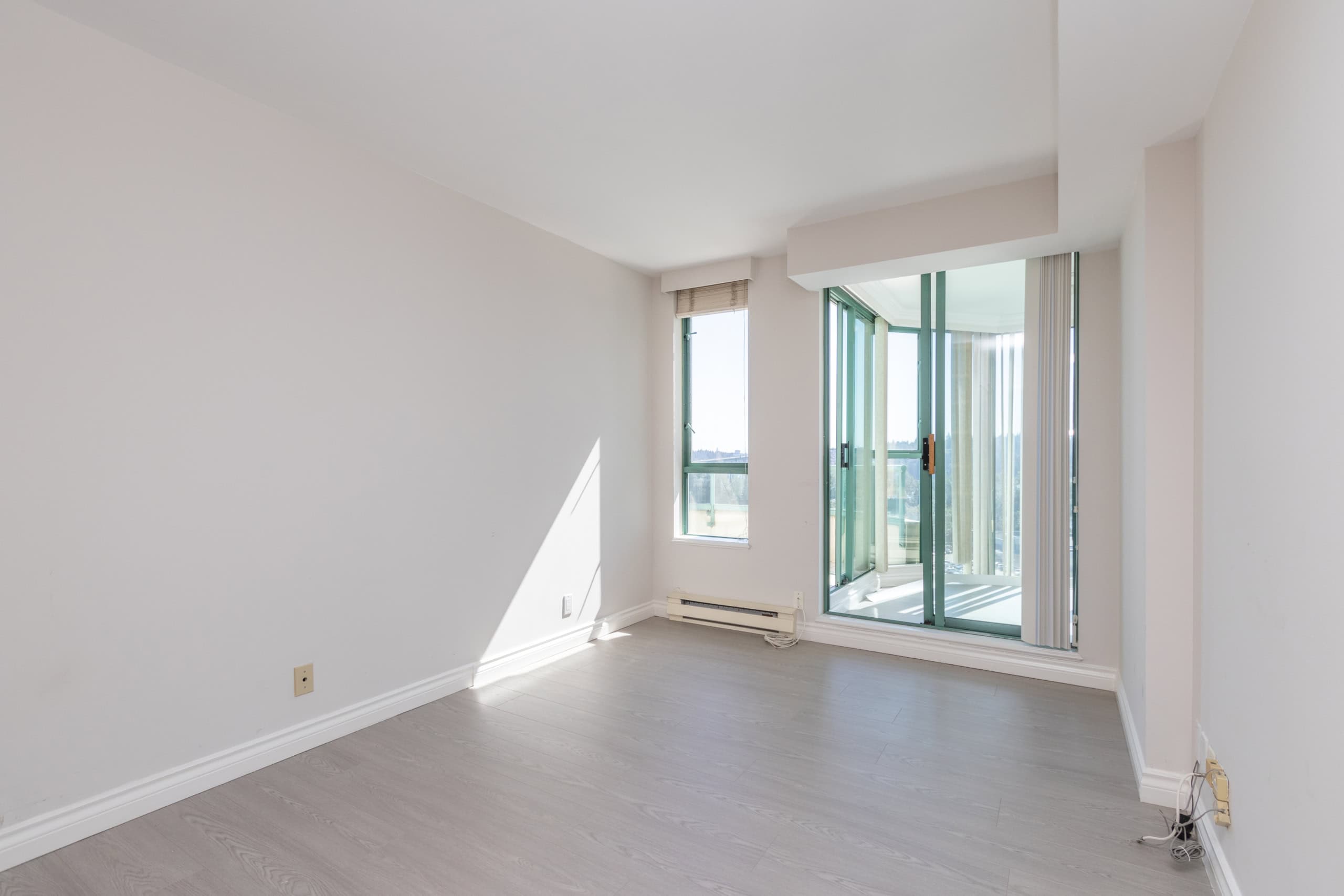 Bright unfurnished living room with large windows and balcony access, showcasing a spacious, modern interior with natural light in Vancouver residential property, ideal for real estate listings.