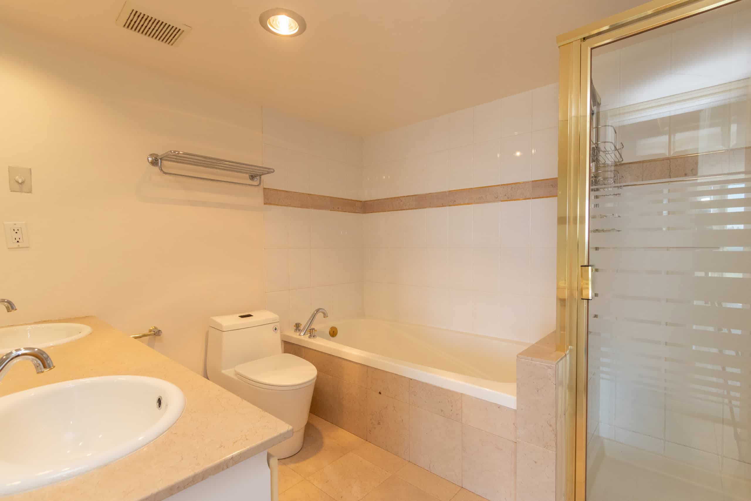 Bright bathroom with double sinks, bathtub, and separate glass shower, featuring modern fixtures and neutral tile decor, perfect for Toronto real estate listings.