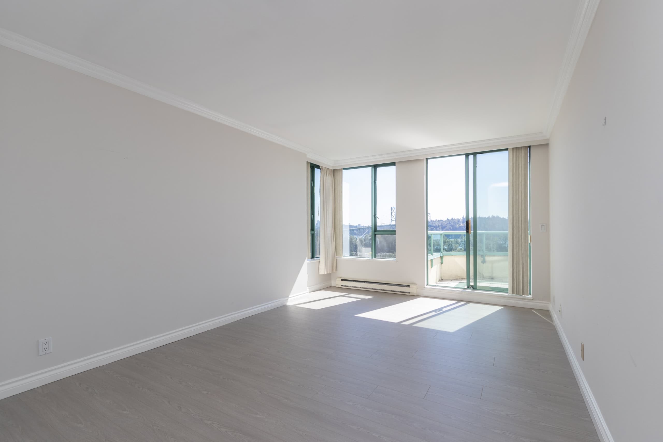 Bright, spacious living room with large windows and balcony overlooking scenic views, ideal for Vancouver real estate.