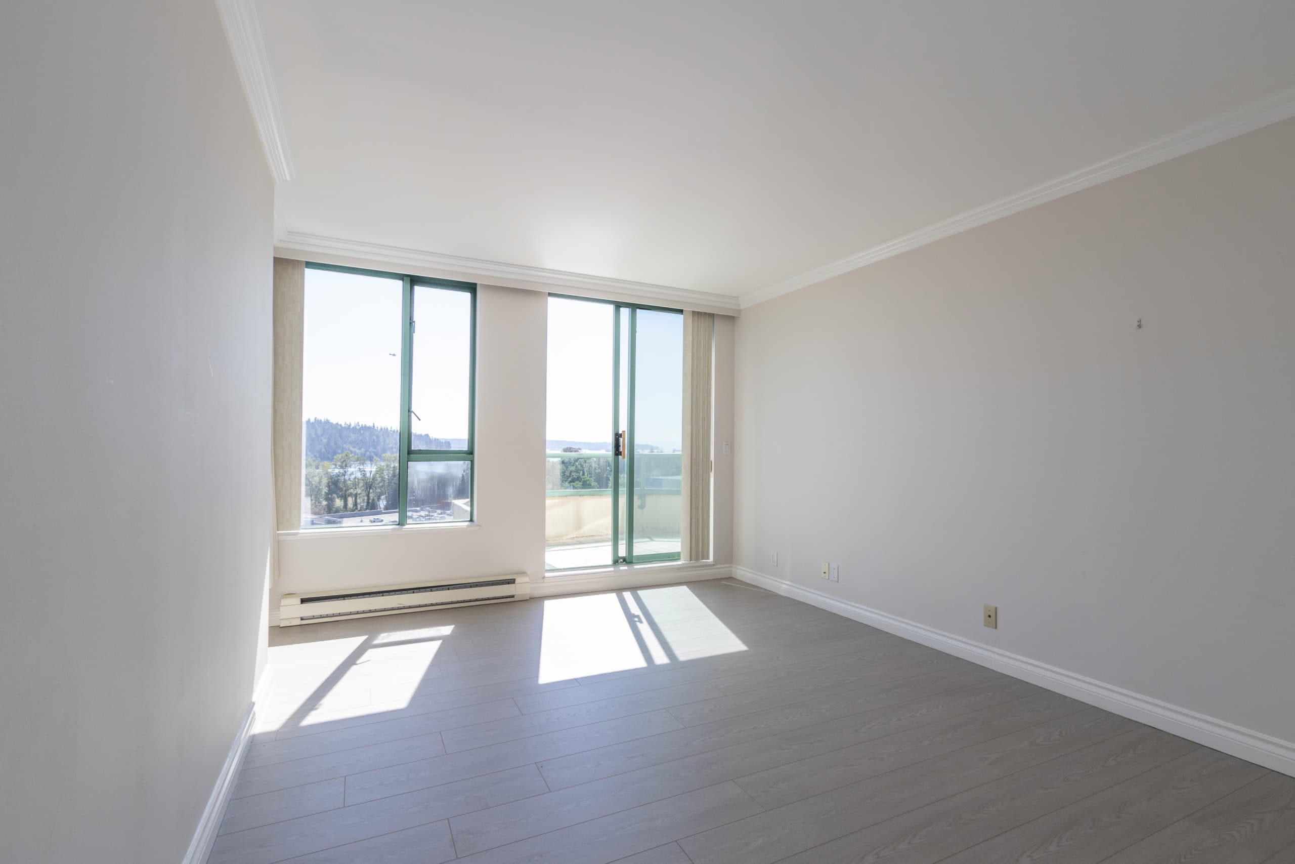 Bright and spacious living room in a modern apartment with large windows and balcony access, offering stunning views. Ideal for comfortable living and indoor-outdoor entertainment.
