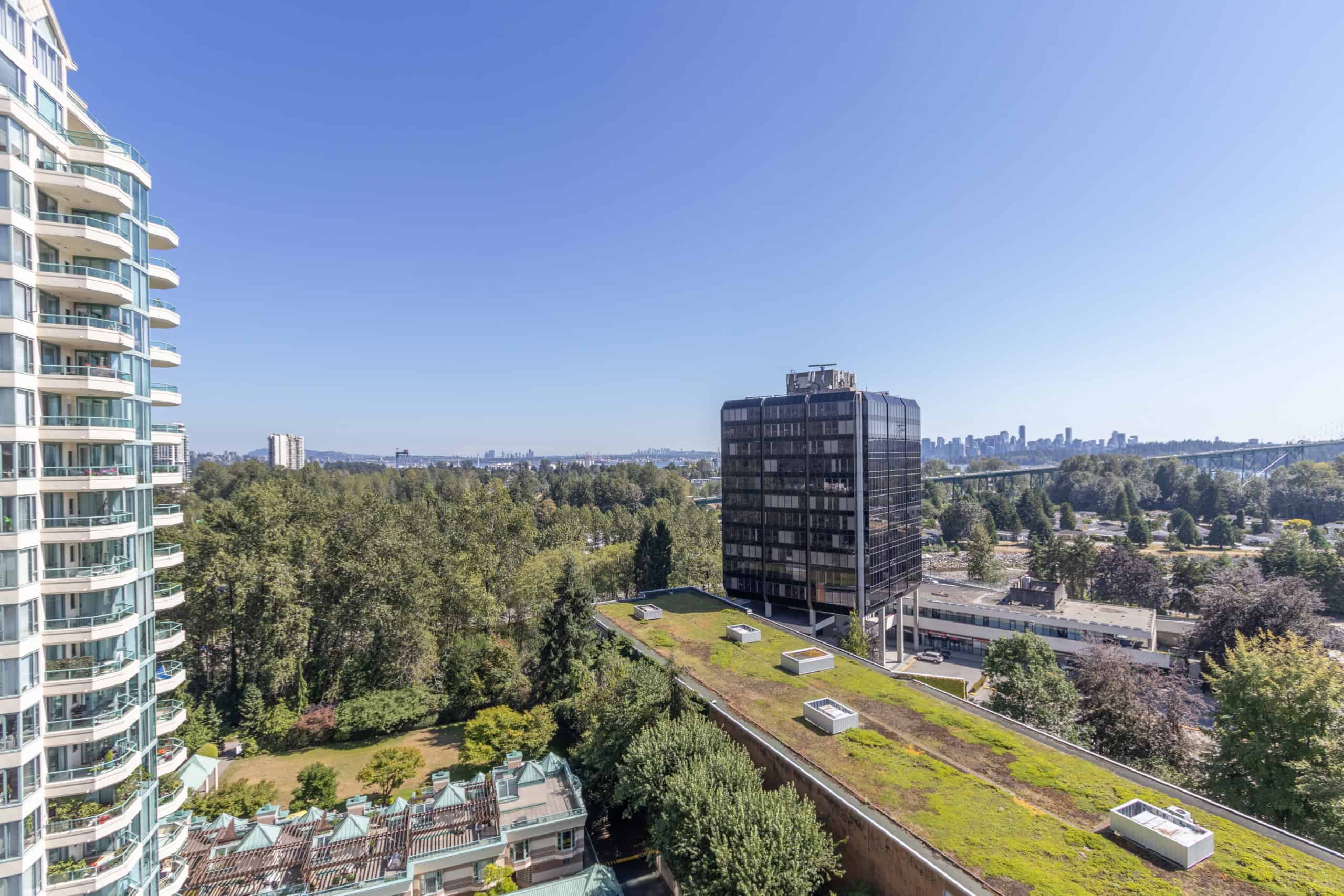 Modern Vancouver city view from high-rise condo, showcasing urban skyline, lush green trees, and contemporary real estate properties with Orca Realty Inc. branding.