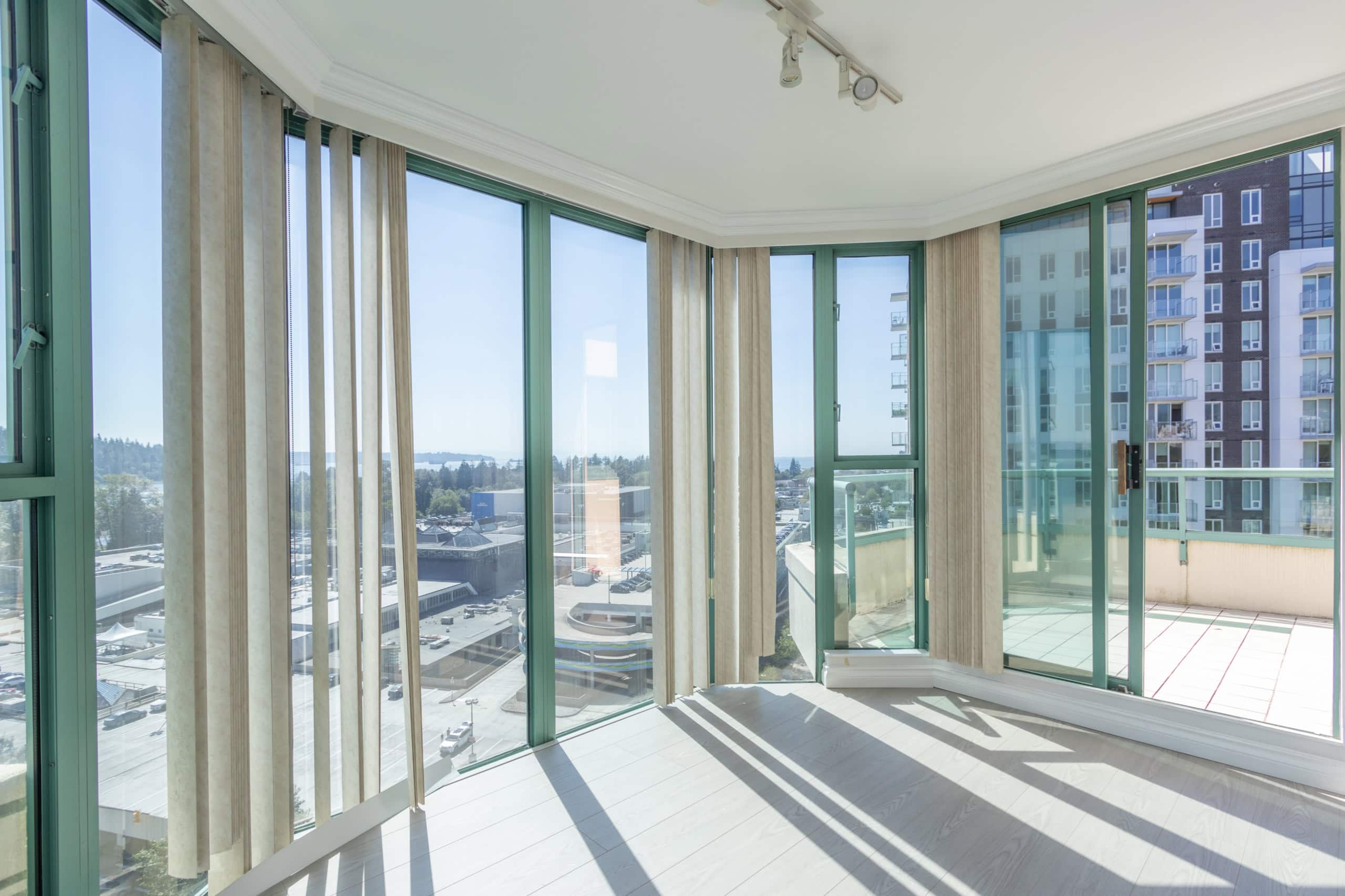 Bright interior view of modern condo with floor-to-ceiling windows and balcony, showcasing Vancouver skyline and water views, perfect for Vancouver real estate and property investments.