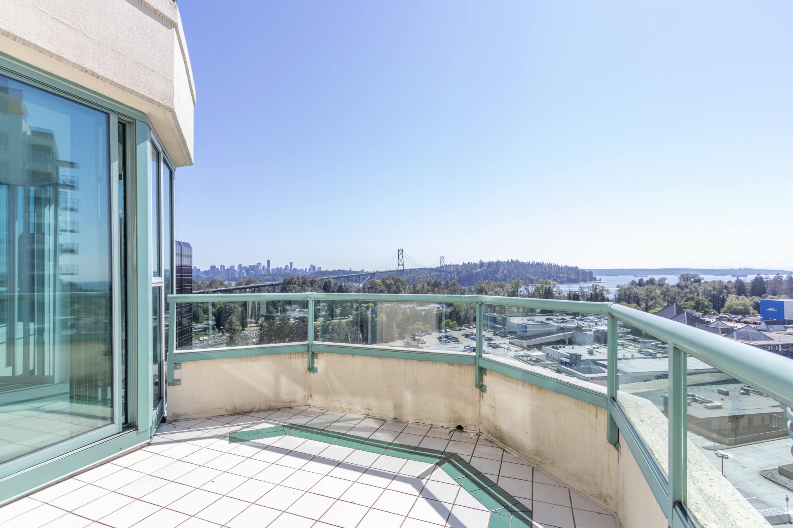 Panoramic view from a high-rise apartment balcony showcasing the Vancouver skyline, bridge, and surrounding greenery, ideal for luxury real estate and property investment in BC.