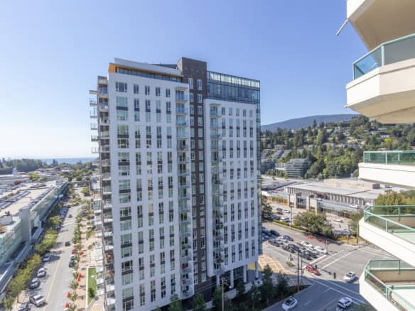 Modern high-rise condominium building in Vancouver with spacious balconies and scenic mountain views, showcasing prime real estate opportunities in BC.