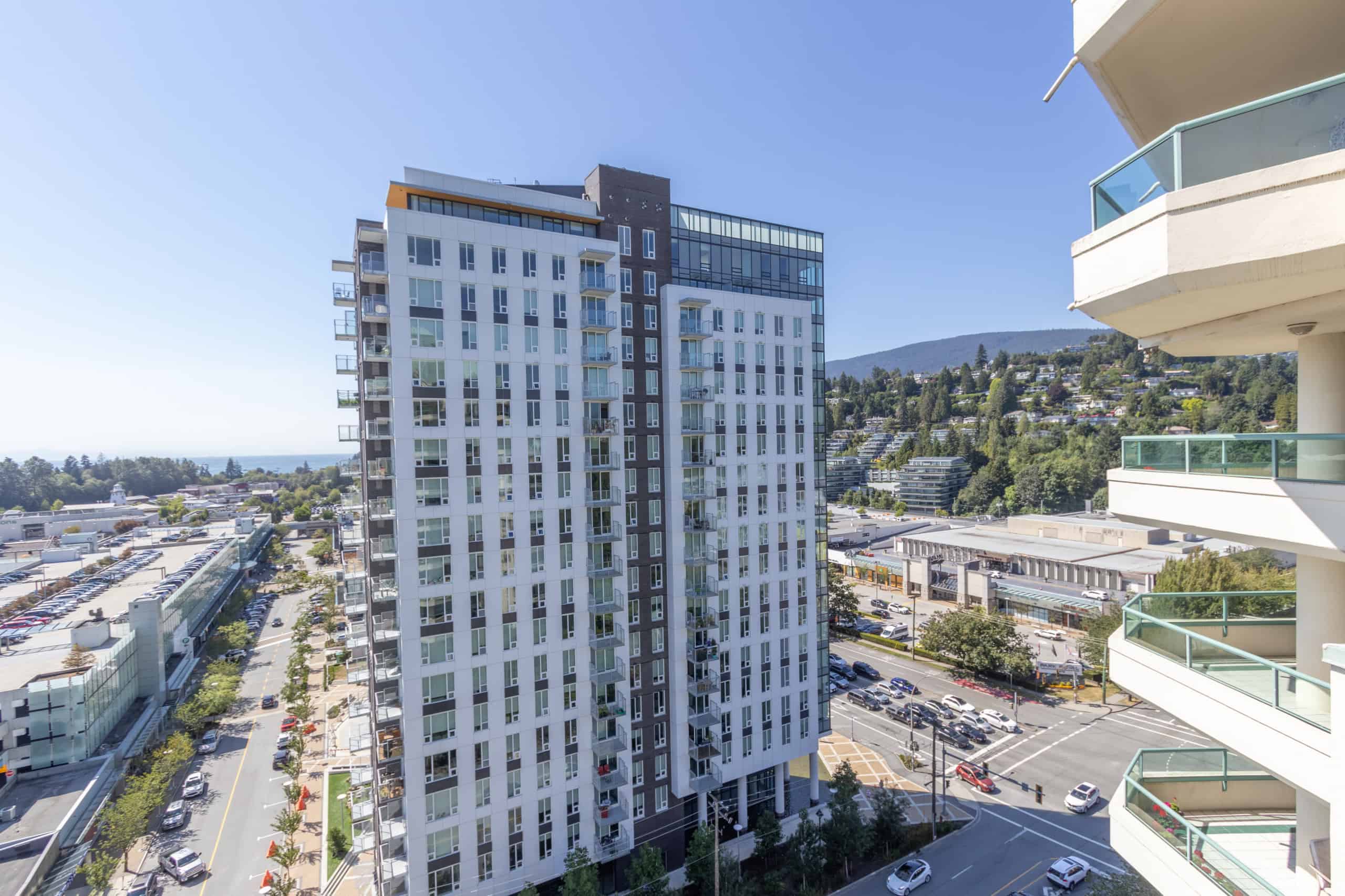 Modern high-rise condominium building in Vancouver with spacious balconies and scenic mountain views, showcasing prime real estate opportunities in BC.