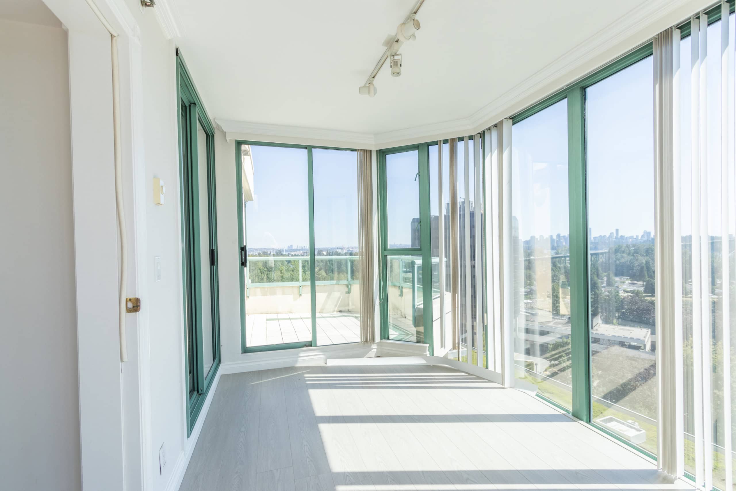 Stunning panoramic views from a modern high-rise condo with floor-to-ceiling windows and a spacious balcony, ideal for Vancouver real estate buyers.