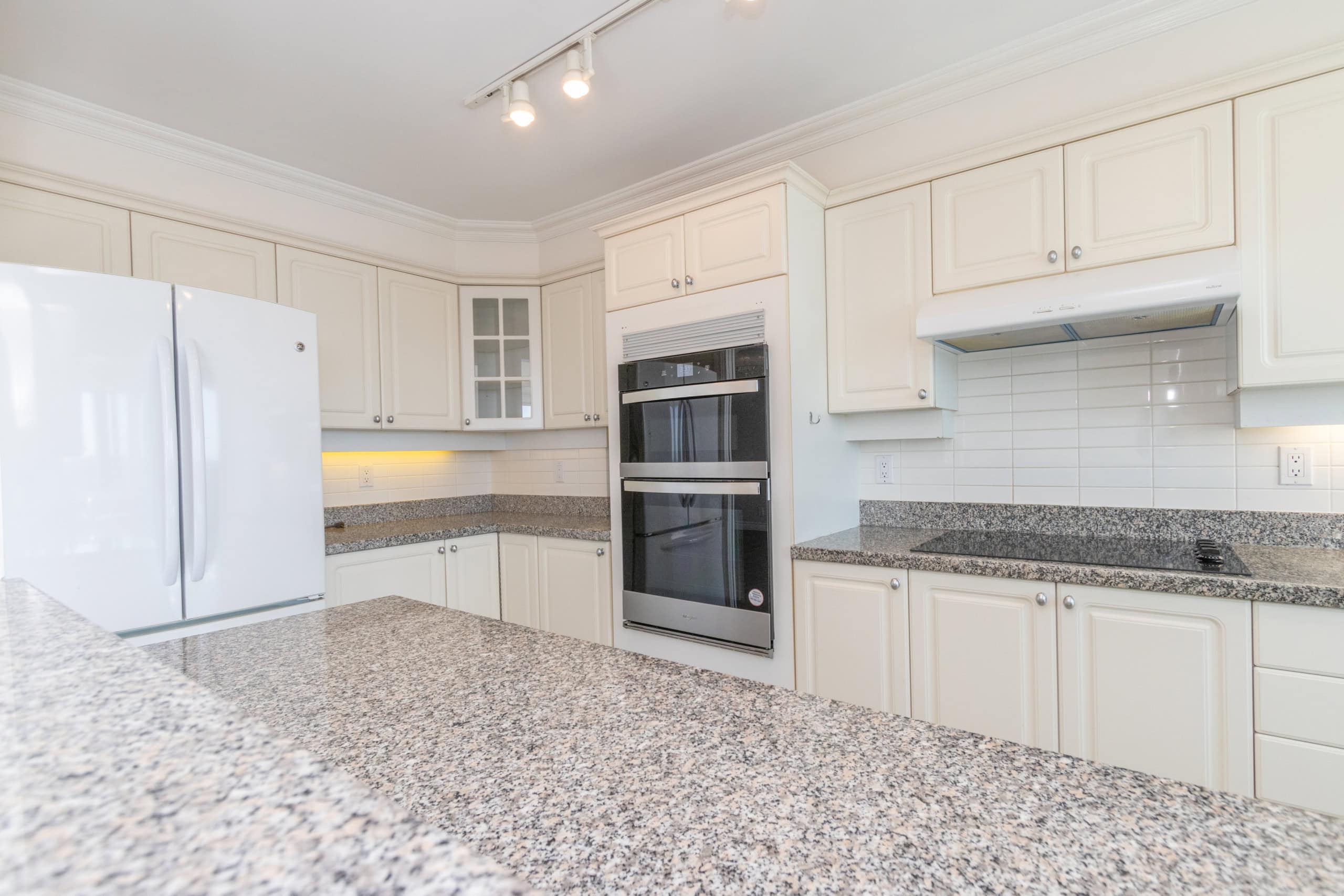 Bright white kitchen with granite countertops, double oven, and ample cabinetry, perfect for Vancouver Island real estate listings.