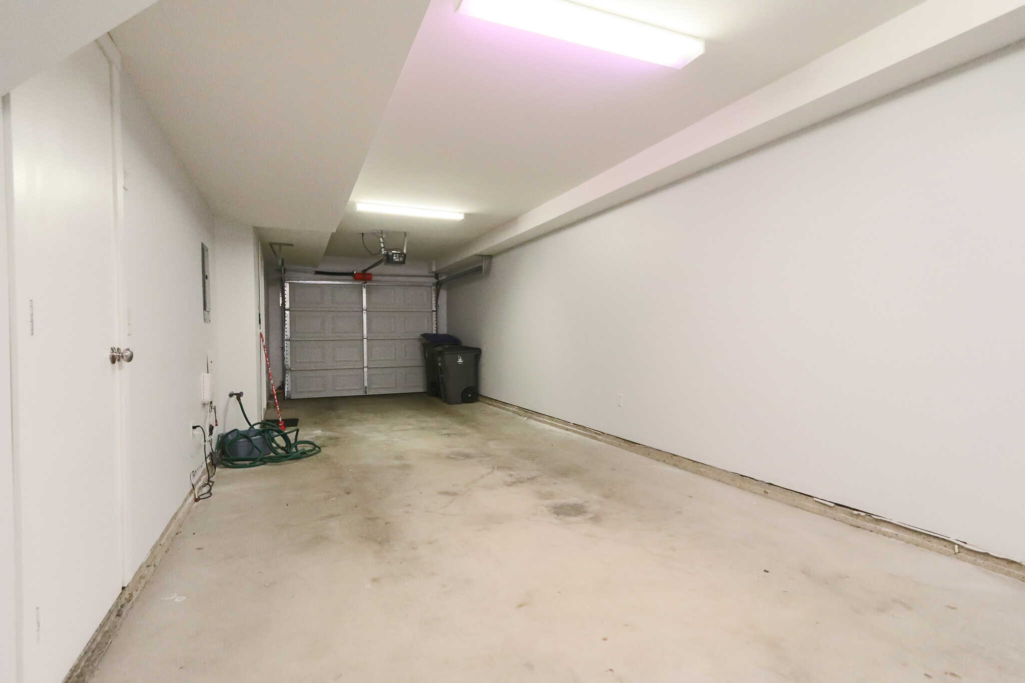 Spacious, clean two-car garage with concrete floor and garage door, perfect for storage or parking at Orca Realty Inc. in British Columbia.