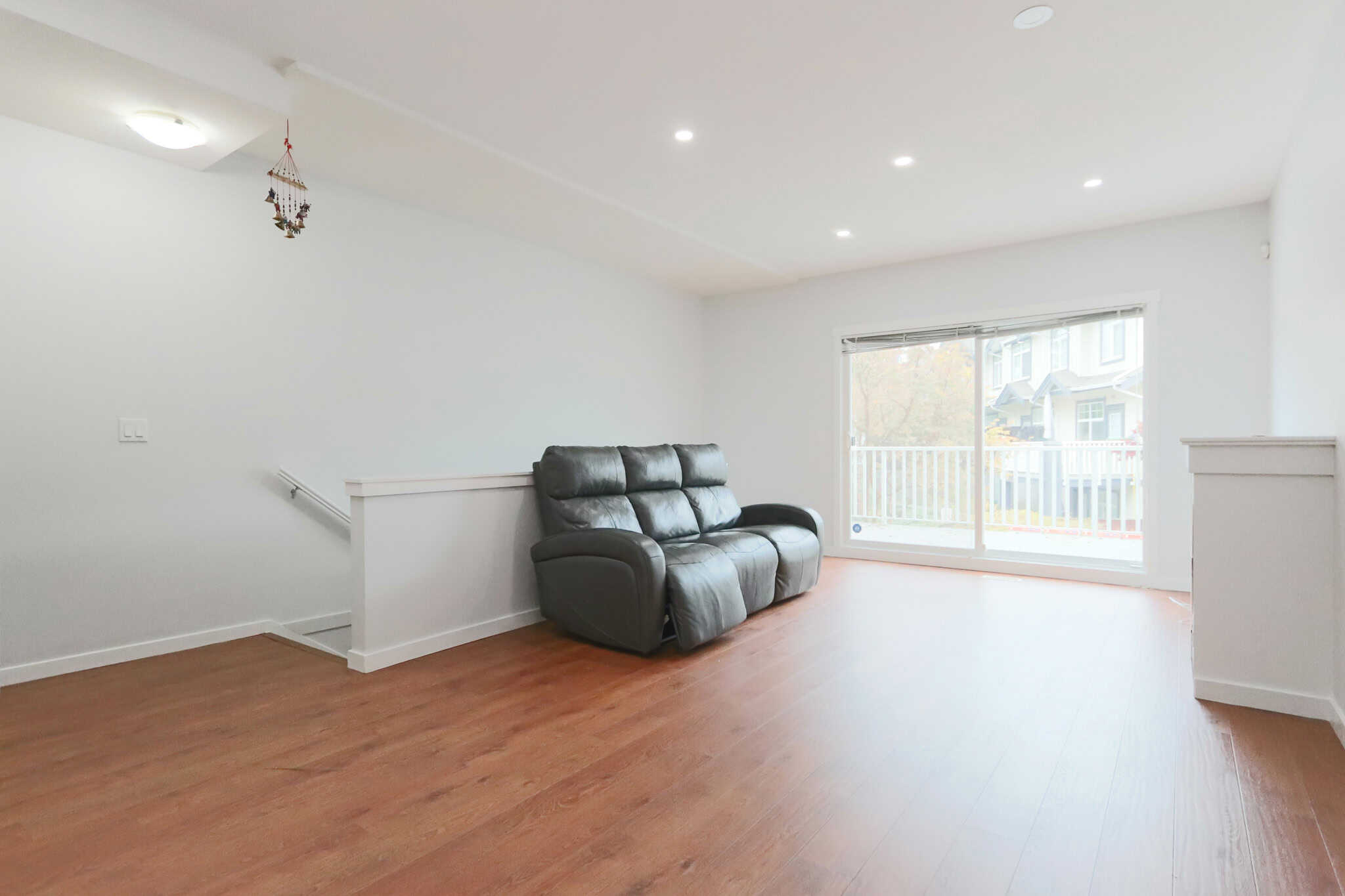 Quiet living room with large sliding glass doors, natural light, hardwood flooring, and modern interior, ideal for Vancouver Island real estate and property investments.