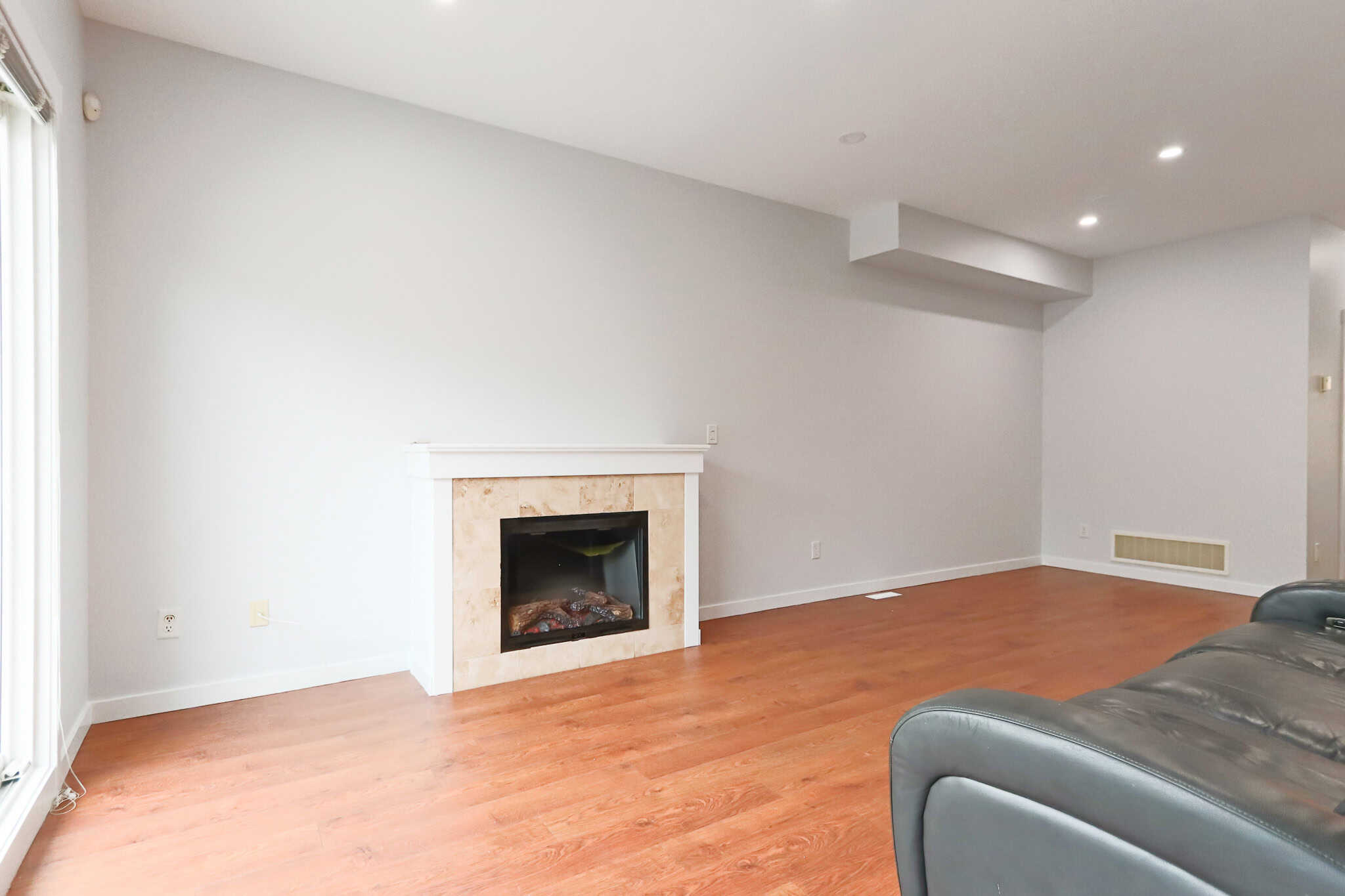 Spacious living room with modern fireplace, white walls, hardwood floors, and natural light, ideal for comfortable family living and urban real estate in CA.