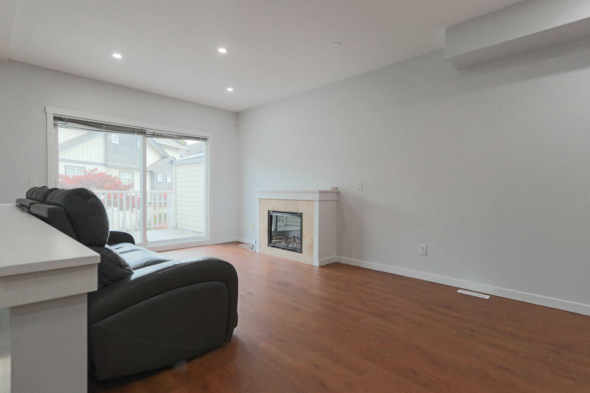 Spacious living room with hardwood flooring, fireplace, and large sliding glass door overlooking the backyard, ideal for homebuyers seeking comfort and natural light.