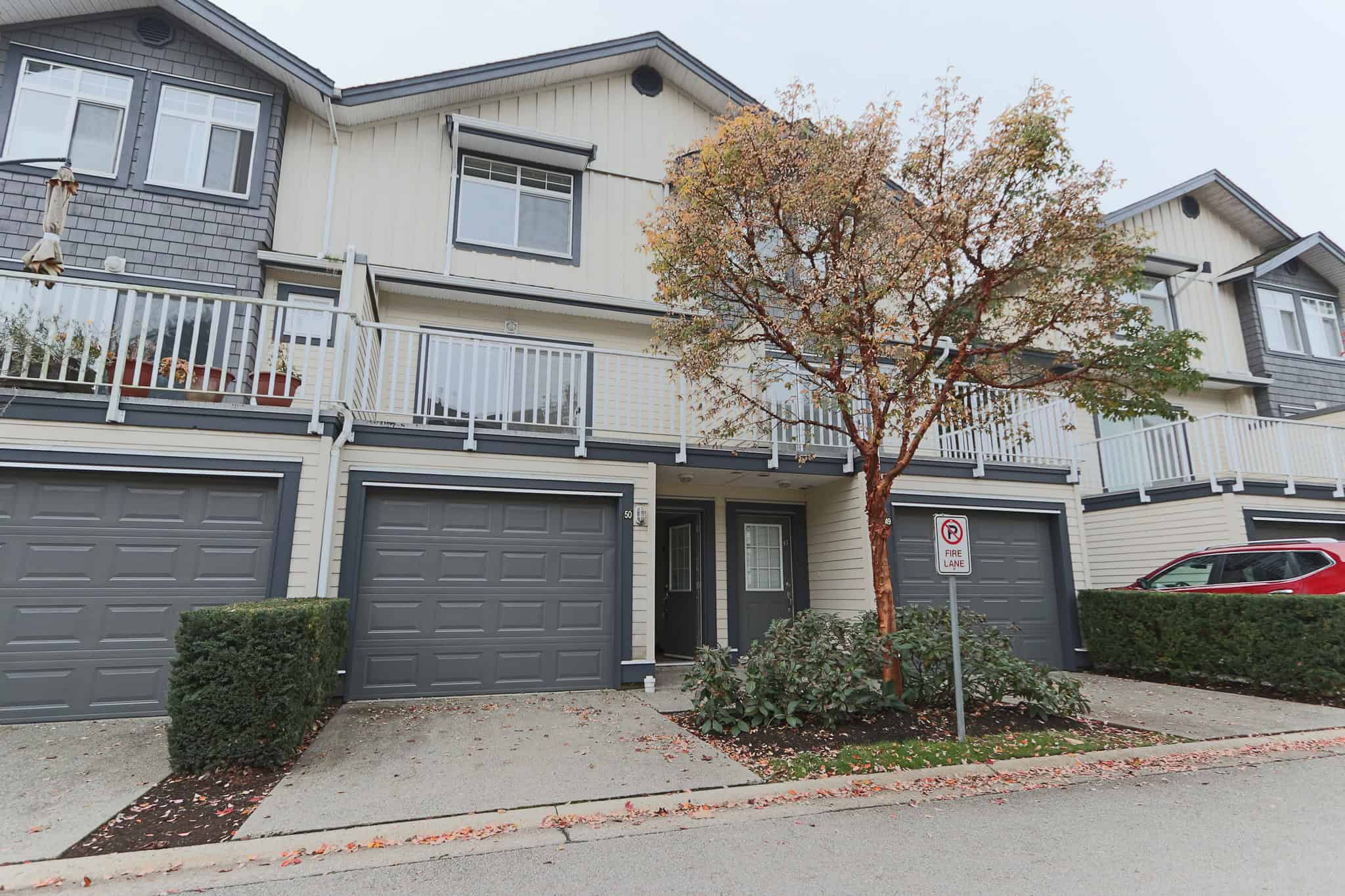 Spacious multi-level townhouse with attached garage, modern exterior, and outdoor balcony, located in a desirable neighbourhood with trees and well-maintained landscaping.