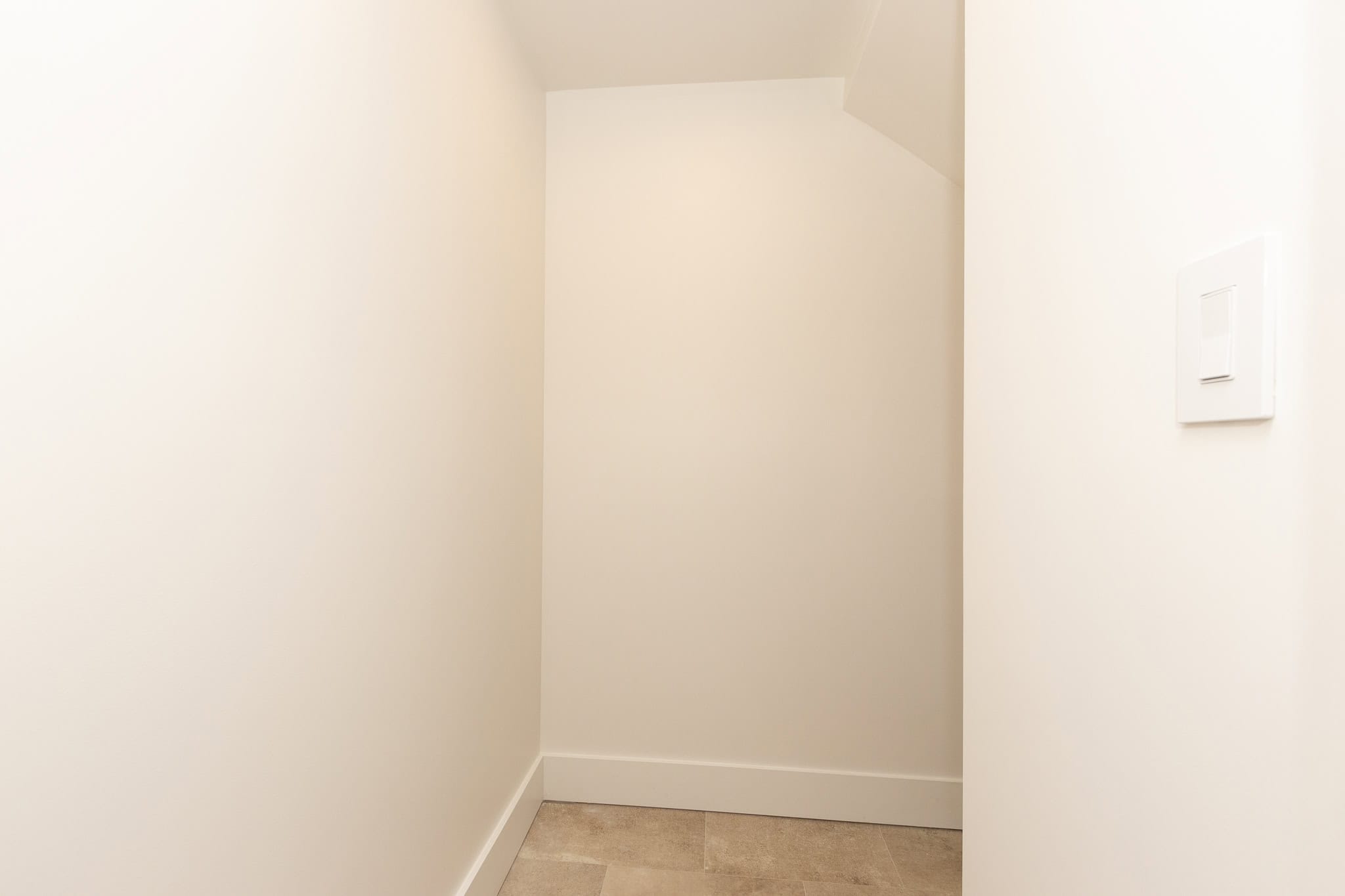 Bright, minimalist interior space featuring clean white walls, subtle baseboards, and neutral flooring, ideal for showcasing professional real estate listing images by Orca Realty Inc.