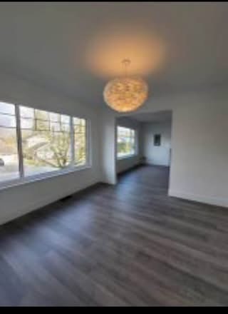 Bright, spacious living room with large windows and modern light fixture in a freshly renovated home by Orca Realty Inc.