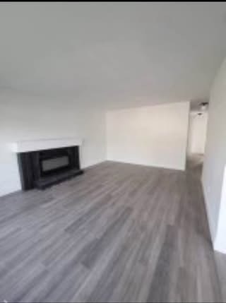 Spacious empty living room with modern flooring and fireplace in a Vancouver area home. Perfect for buyers seeking contemporary residential properties.