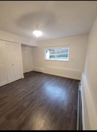 Bright empty living room with hardwood floors, white walls, a window for natural light, and a closet, showcasing available real estate listings by Orca Realty Inc.