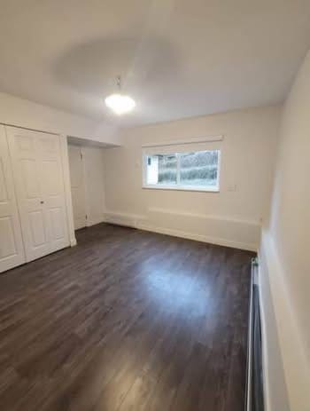 Bright empty bedroom with white walls, large window, and laminate flooring, perfect for homebuyers seeking a tranquil living space in the Greater Vancouver area.