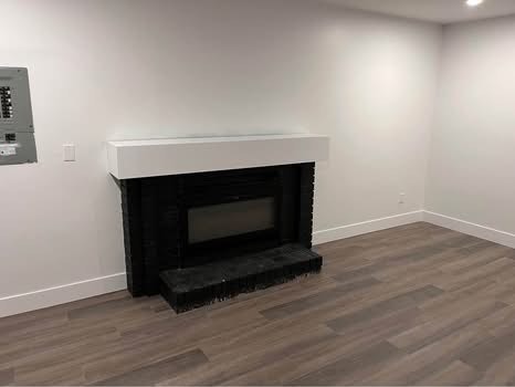 Minimalist fireplace with black surround and white mantel in modern living room, showcasing upscale interior design for Vancouver and BC real estate markets.