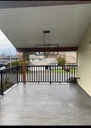 Bright covered balcony with ceiling fan, overlooking a suburban neighbourhood, ideal for relaxing or outdoor entertaining in Vancouver Island.