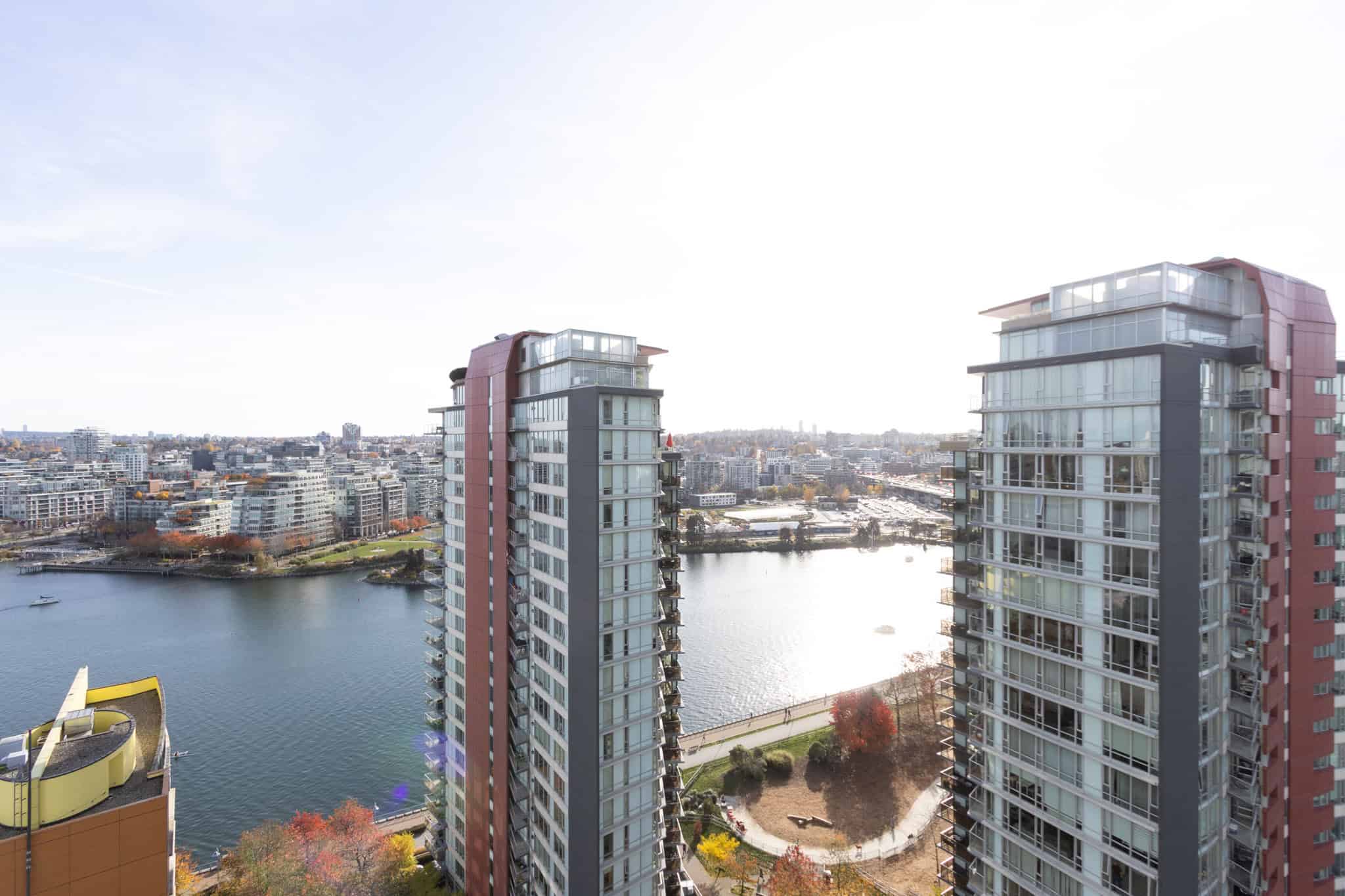 Modern waterfront high-rise condo buildings with panoramic city and river views in Vancouver, BC, showcasing luxury residential real estate by Orca Realty Inc.