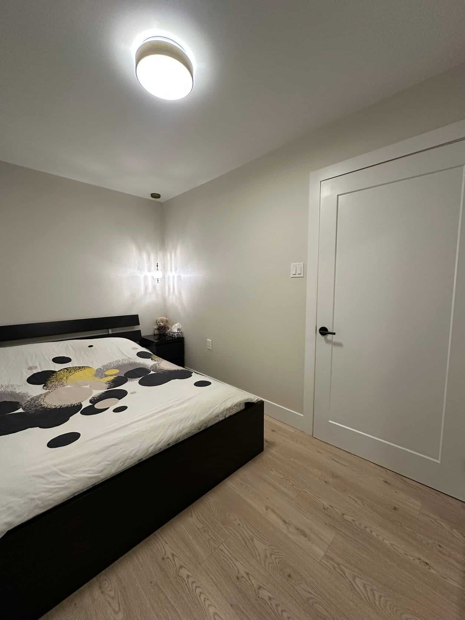 Modern bedroom interior with minimalist design, featuring a black bed frame, a stylish bedding with geometric circles, and soft lighting, showcasing Orca Realty Inc.'s residential real estate expertise.