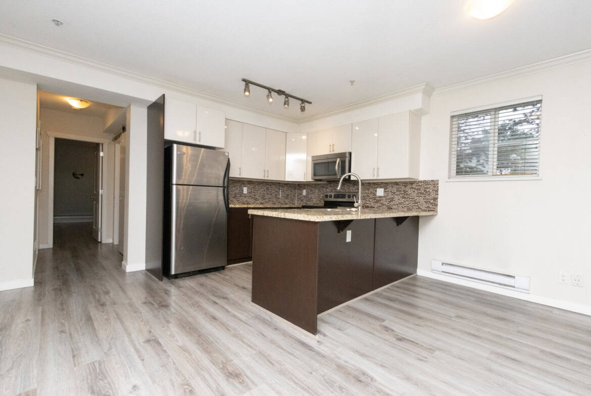 Bright modern kitchen with stainless steel appliances, granite countertops, white cabinets, and sleek design, ideal for Toronto real estate buyers seeking contemporary condo living in Canada.