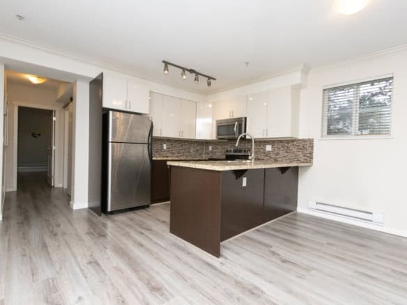 Bright modern kitchen with stainless steel appliances, granite countertops, white cabinets, and sleek design, ideal for Toronto real estate buyers seeking contemporary condo living in Canada.