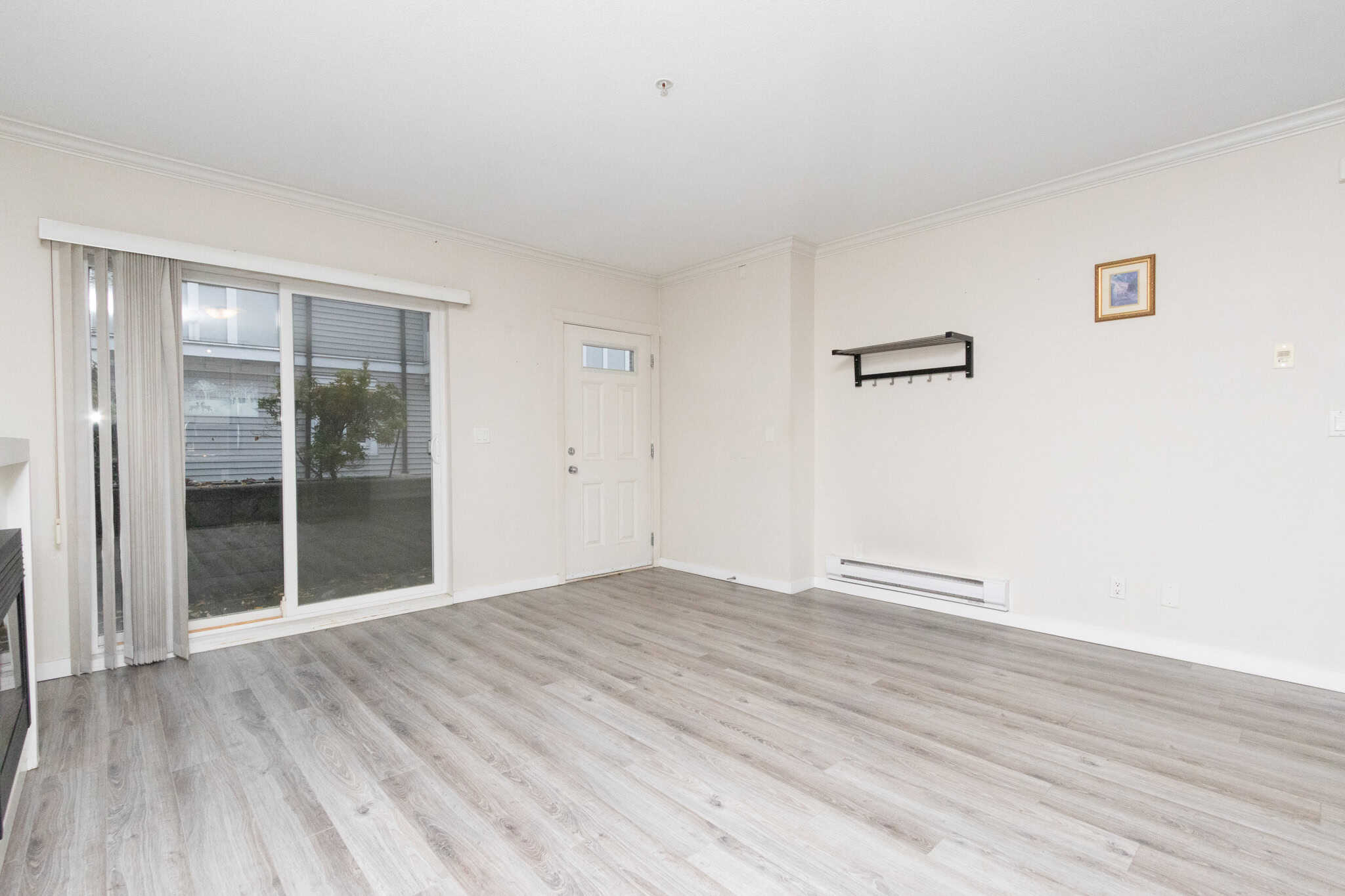 Bright living room with sliding glass door, laminate flooring, and neutral walls, perfect for Vancouver real estate investments or residential properties in BC.