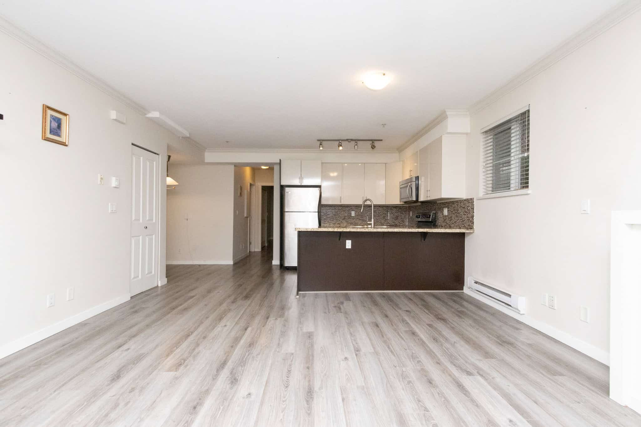 Bright open-concept kitchen and living space in an Ottawa condo, featuring modern appliances, stylish cabinetry, and laminate flooring, perfect for comfortable city living.