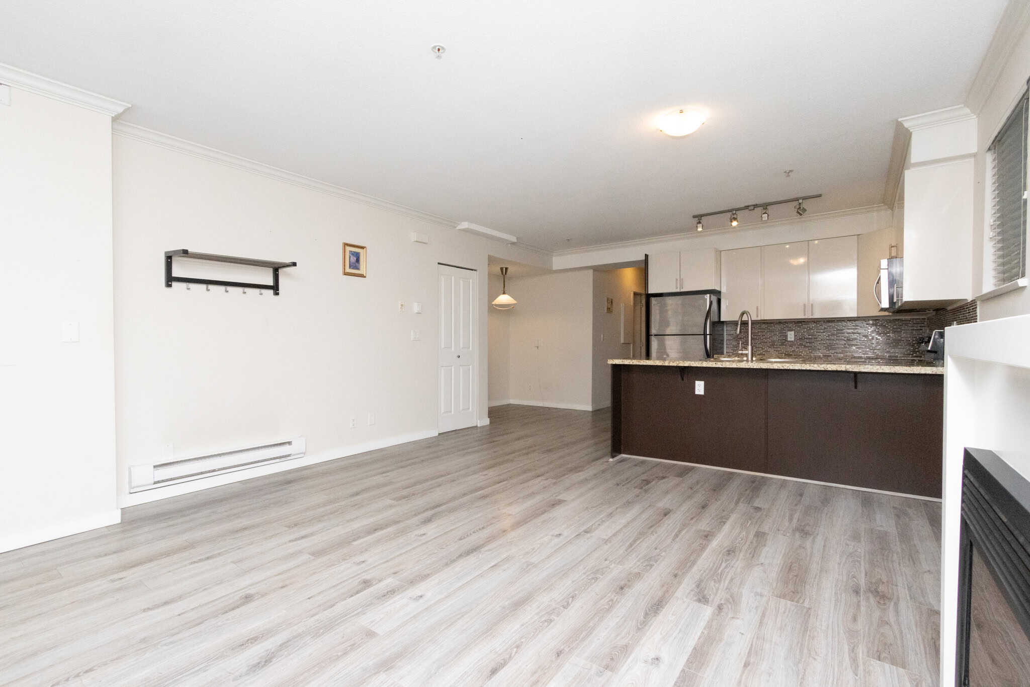 Bright and spacious open-concept apartment in Vancouver featuring modern kitchen with granite countertops, stainless steel appliances, and hardwood flooring, ideal for comfortable living and real estate investment.