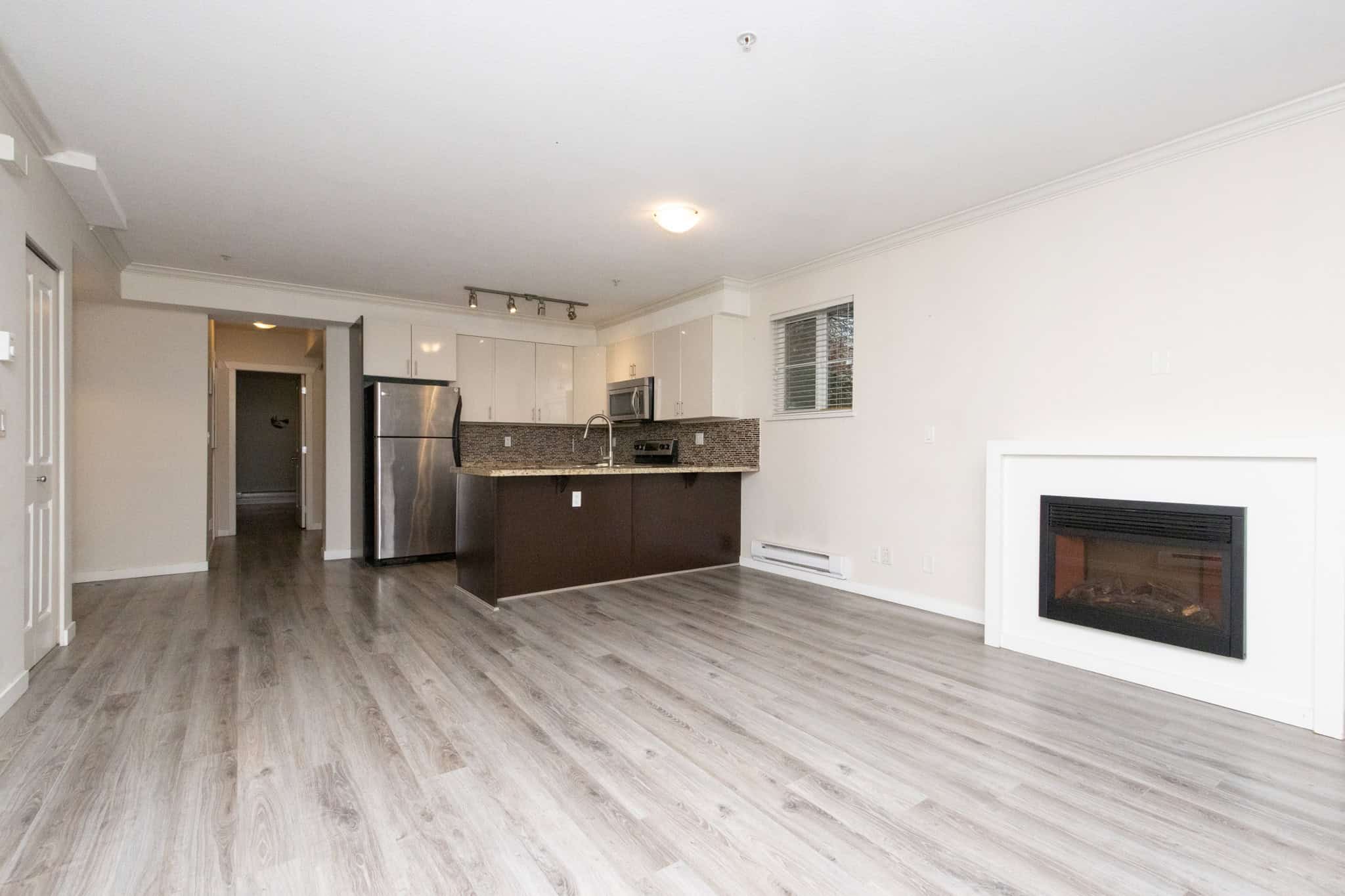 Bright open-concept living space with modern kitchen, fireplace, and laminate flooring, perfect for Vancouver Island real estate and homebuyers seeking contemporary condos or apartments.