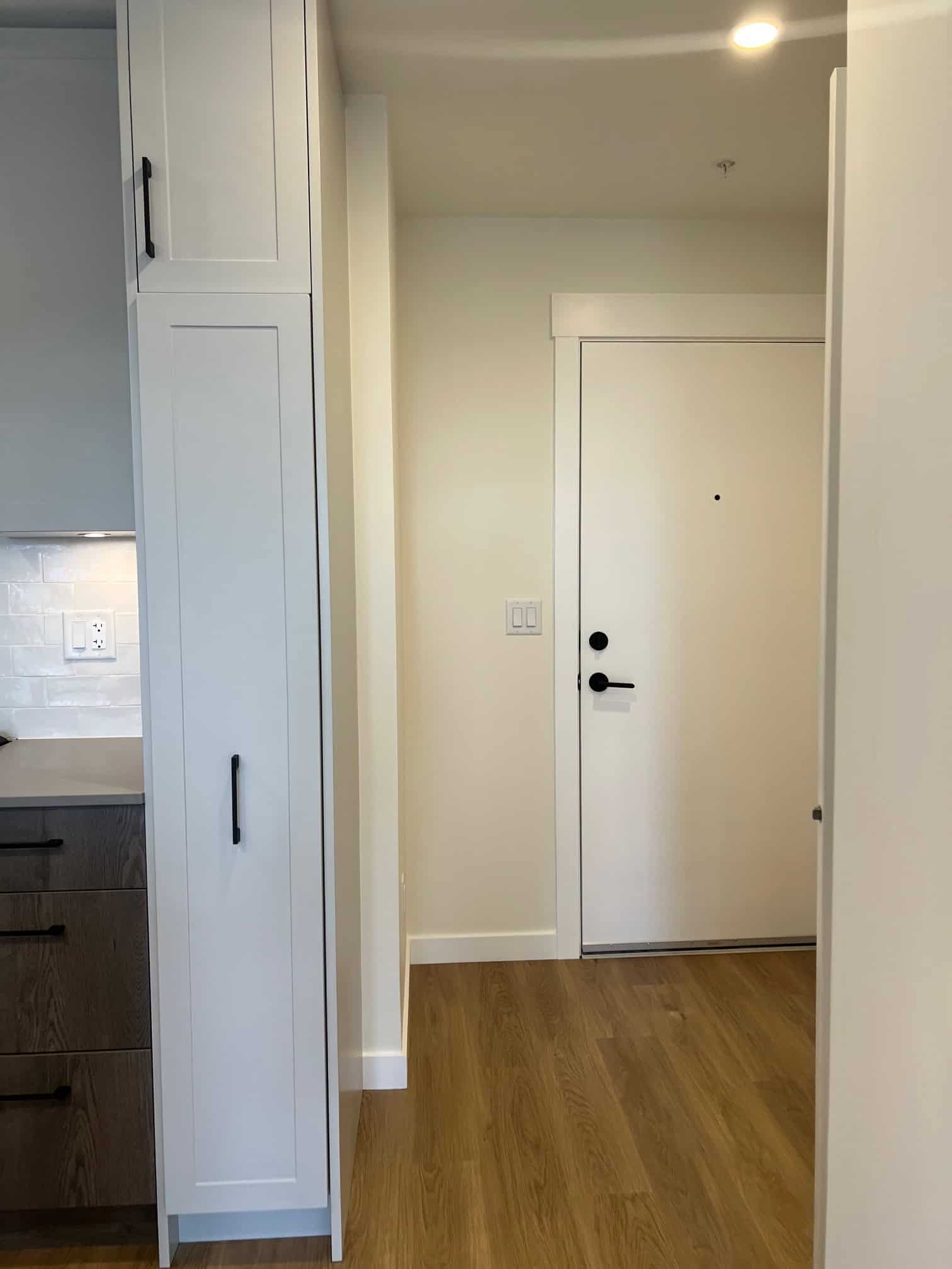 IMG_5601 Modern kitchen interior with white cabinetry and wooden flooring, showcasing high-quality finishes in a listed property by Orca Realty Inc. for optimal real estate SEO.