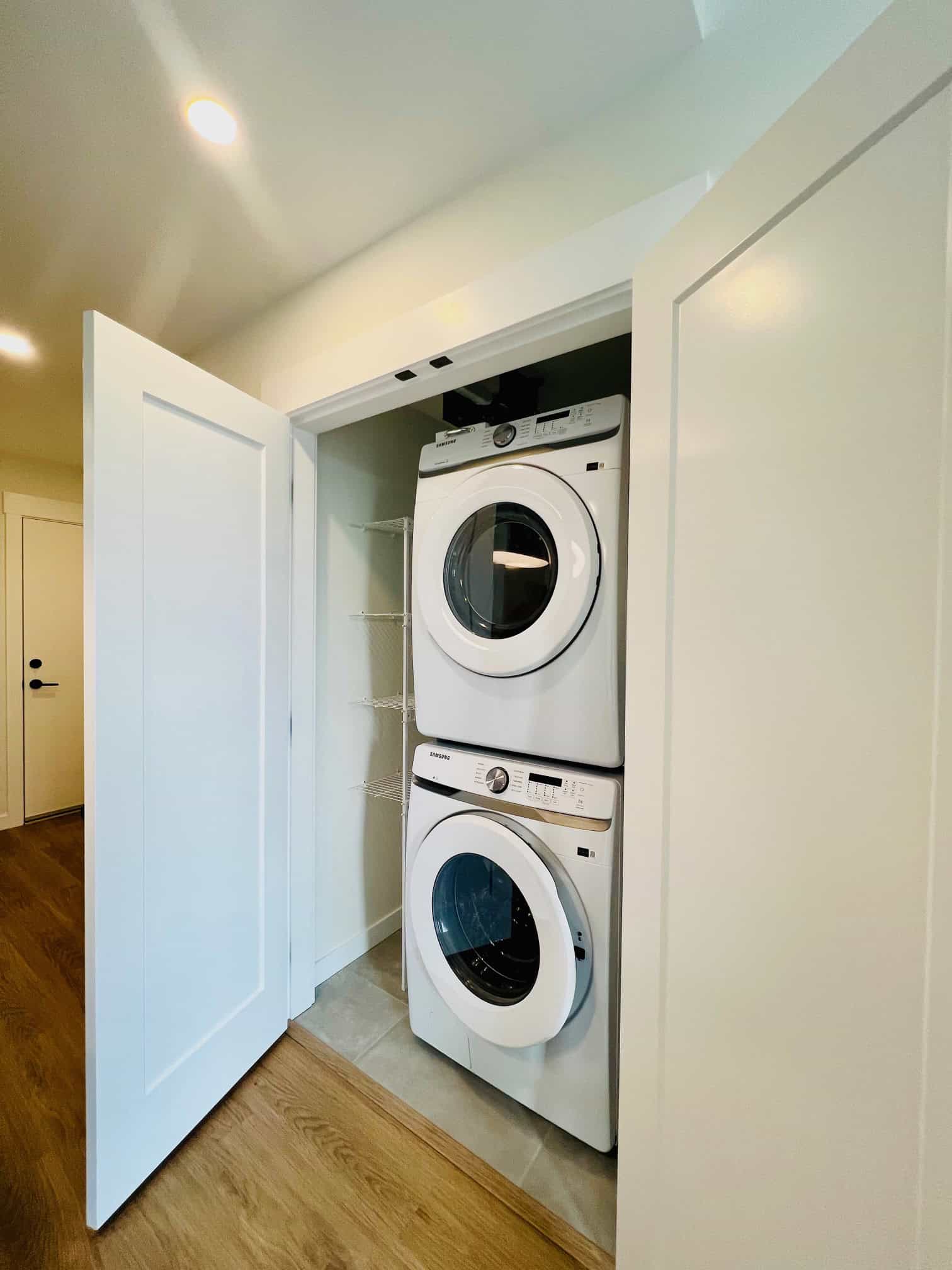 IMG_5613 Stacked washer and dryer in a compact laundry nook, featuring white appliances inside a closet with bi-fold doors, ideal for a modern home or property listing on Orca Realty Inc.