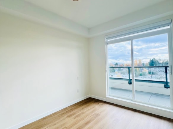 Bright and airy apartment interior with large sliding glass door leading to a balcony, showcasing stunning city views, perfect for Vancouver real estate listings.