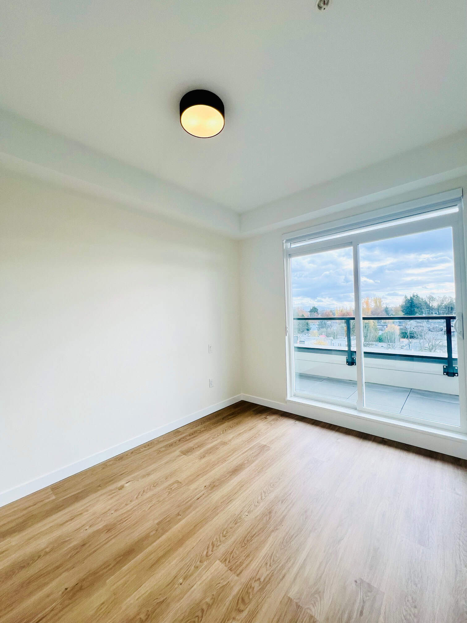 IMG_5614 Bright and airy apartment interior with large sliding glass door leading to a balcony, showcasing stunning city views, perfect for Vancouver real estate listings.