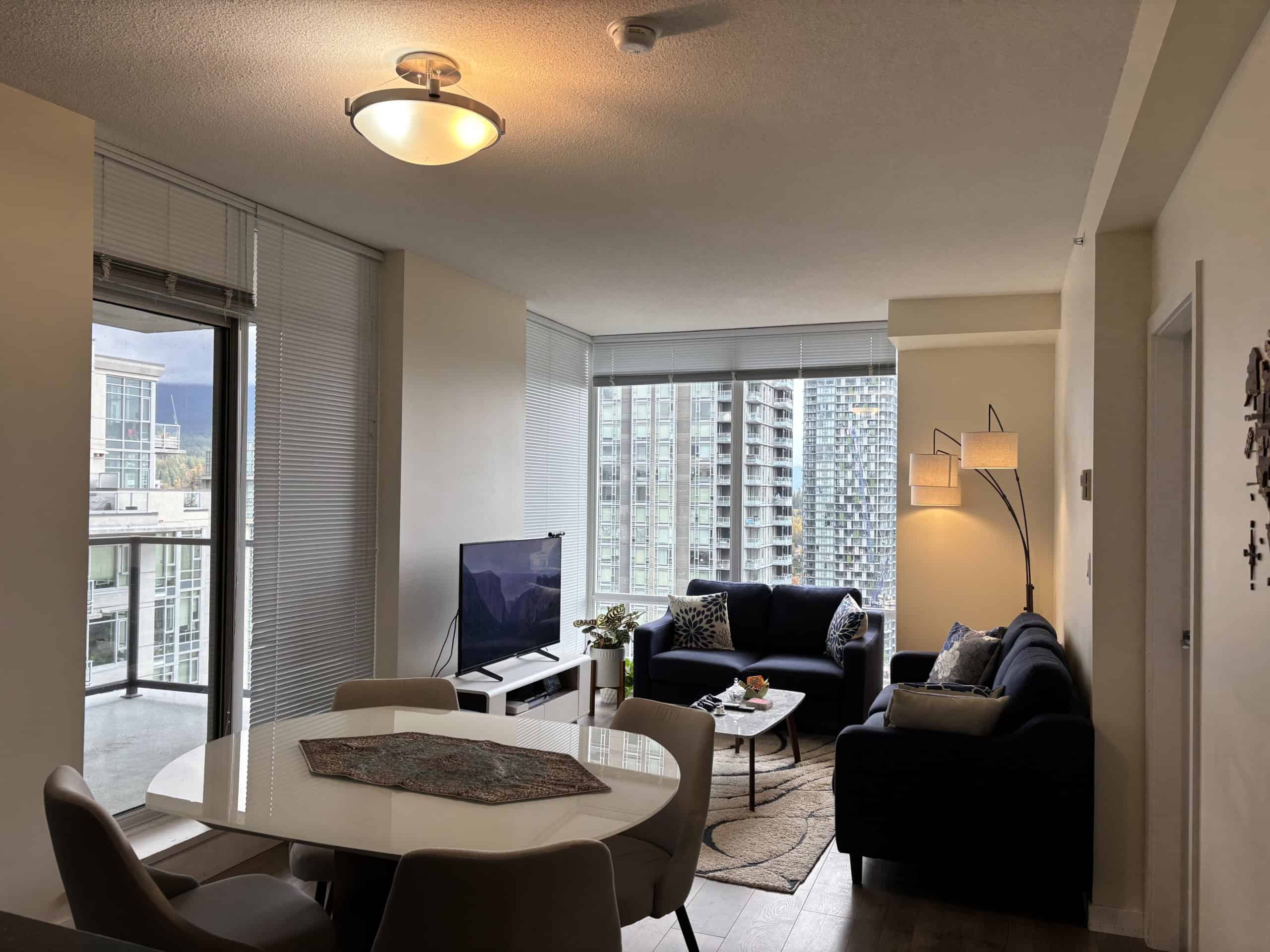 Bright living room in modern Vancouver condo with large windows, city views, comfortable seating, and contemporary decor, ideal for relaxed urban living.