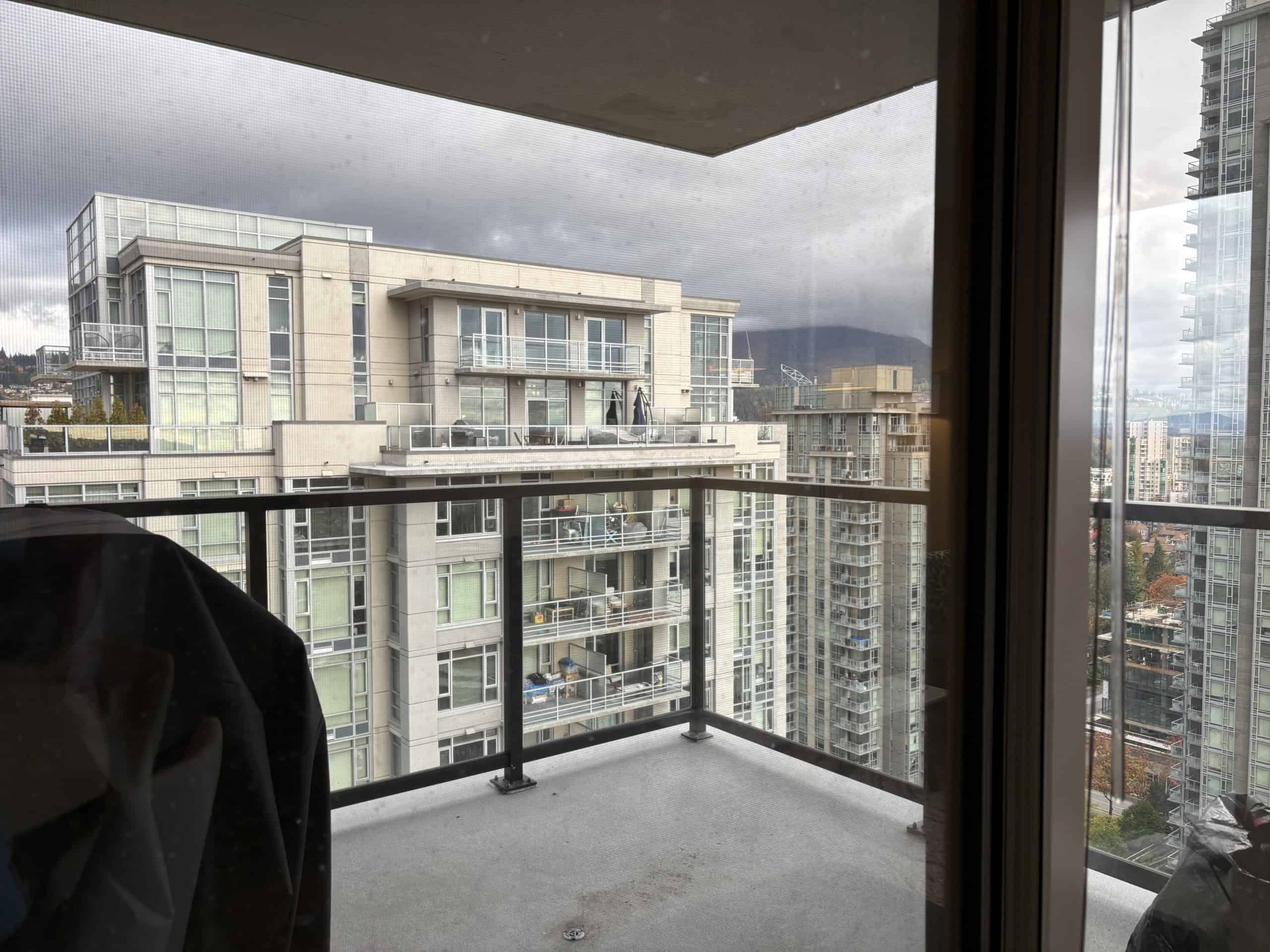 Modern Vancouver condo balcony overlooking high-rise buildings with mountain views, ideal for urban living and real estate investments in BC.